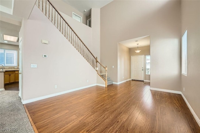 unfurnished living room featuring hardwood / wood-style flooring and a towering ceiling