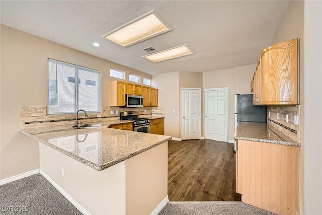 kitchen with sink, decorative backsplash, light stone countertops, and appliances with stainless steel finishes