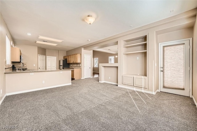 unfurnished living room featuring carpet floors, sink, and built in features