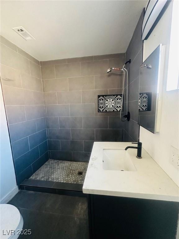 bathroom with vanity, tiled shower, and toilet