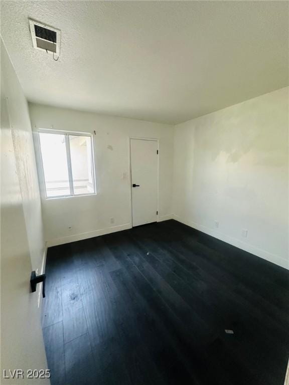 empty room with dark hardwood / wood-style floors and a textured ceiling