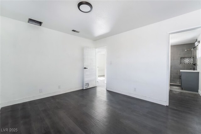 unfurnished bedroom featuring dark hardwood / wood-style floors and connected bathroom