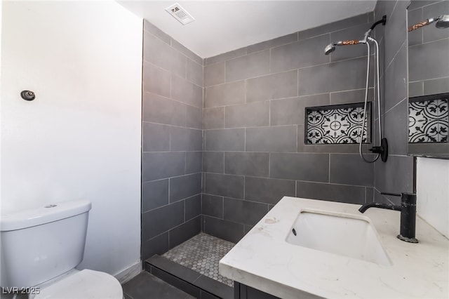 bathroom featuring vanity, toilet, and a tile shower