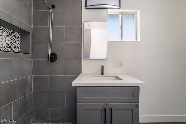 bathroom featuring tiled shower and vanity