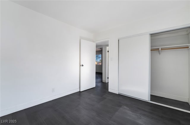 unfurnished bedroom with dark hardwood / wood-style flooring and a closet