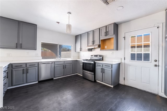 kitchen featuring dark wood-type flooring, sink, gray cabinetry, decorative light fixtures, and appliances with stainless steel finishes