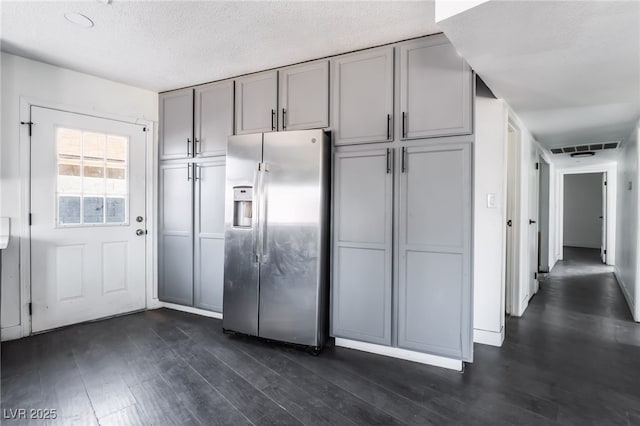 kitchen featuring gray cabinets, a textured ceiling, stainless steel fridge, and dark hardwood / wood-style flooring