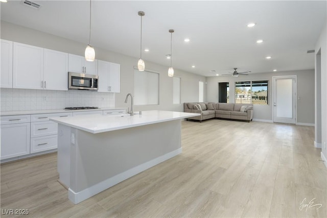 kitchen featuring white cabinetry, sink, an island with sink, and gas cooktop