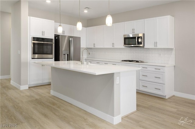 kitchen featuring sink, white cabinetry, an island with sink, pendant lighting, and stainless steel appliances