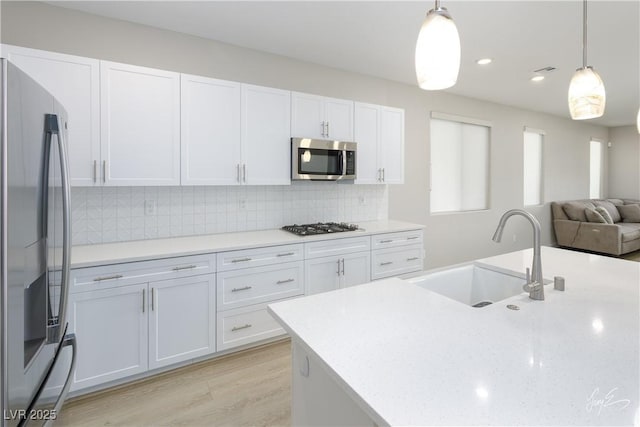 kitchen with stainless steel appliances, sink, hanging light fixtures, and white cabinets