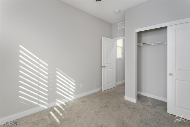 unfurnished bedroom featuring light carpet and a closet