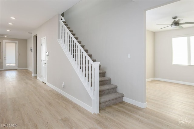 stairway with wood-type flooring and ceiling fan