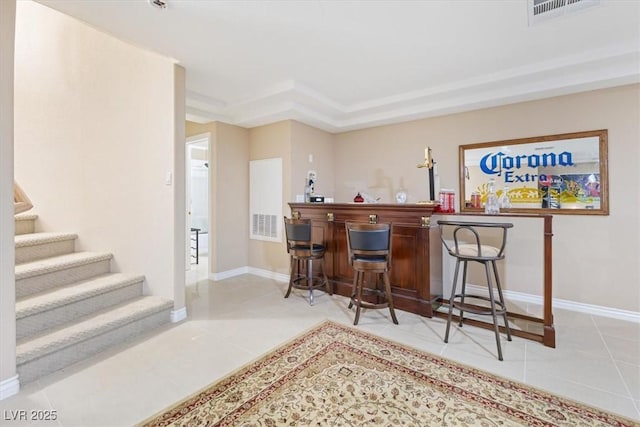 bar with light tile patterned flooring and a tray ceiling