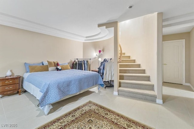 bedroom with a tray ceiling and light tile patterned floors