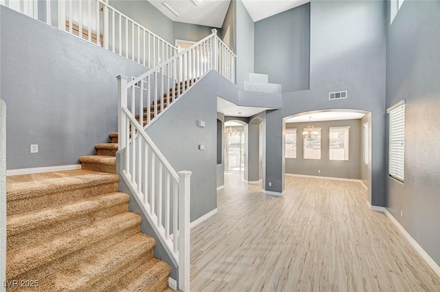 stairway with a high ceiling and wood-type flooring