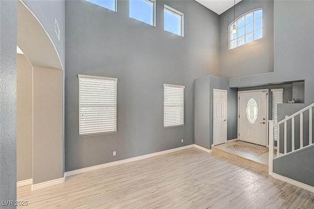 entryway featuring a towering ceiling and light wood-type flooring