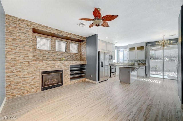 kitchen featuring tasteful backsplash, a kitchen breakfast bar, a kitchen island, pendant lighting, and stainless steel appliances