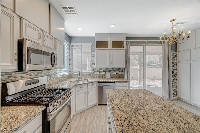 kitchen featuring stainless steel appliances, white cabinetry, and light stone counters