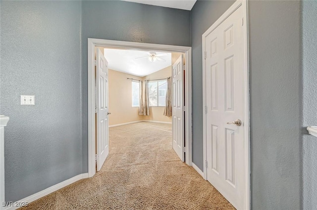 corridor with light carpet and vaulted ceiling