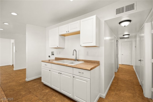 kitchen featuring tile patterned floors, sink, and white cabinets