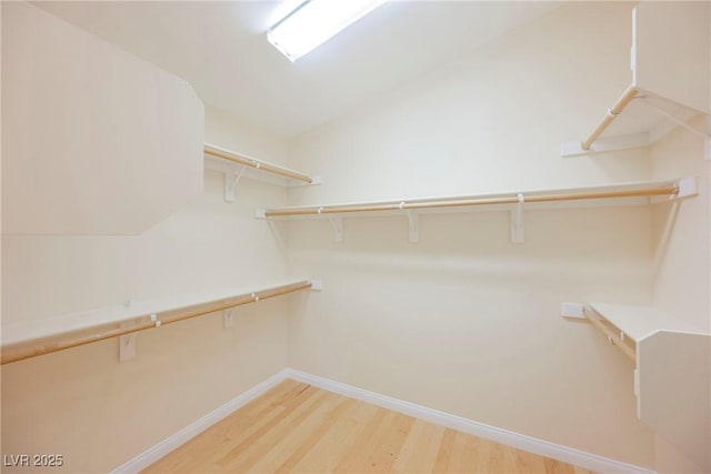 walk in closet with lofted ceiling and light hardwood / wood-style flooring