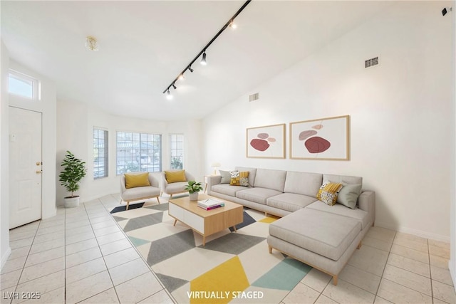 tiled living room with rail lighting and vaulted ceiling