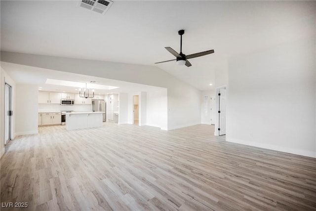 unfurnished living room featuring vaulted ceiling, ceiling fan with notable chandelier, and light wood-type flooring