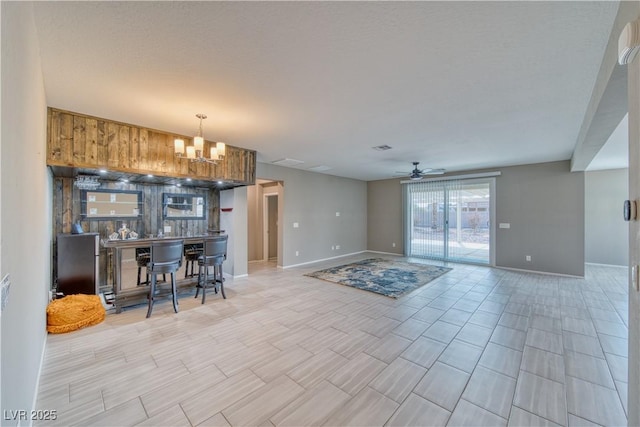 kitchen with ceiling fan with notable chandelier, decorative light fixtures, and a kitchen bar