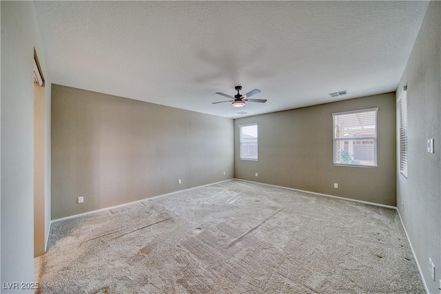 empty room with light colored carpet, ceiling fan, and a textured ceiling