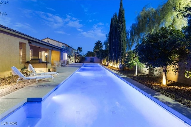 view of pool with exterior kitchen and a patio area