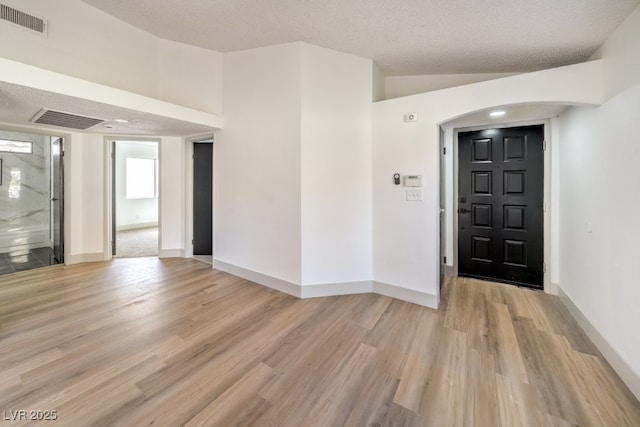 entryway with light wood-type flooring and a textured ceiling