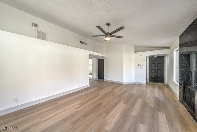 empty room with ceiling fan, wood-type flooring, vaulted ceiling, and a textured ceiling