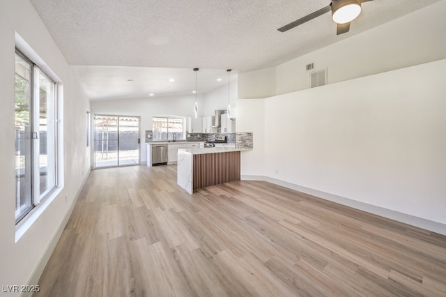 kitchen with pendant lighting, white cabinetry, stainless steel dishwasher, kitchen peninsula, and a textured ceiling