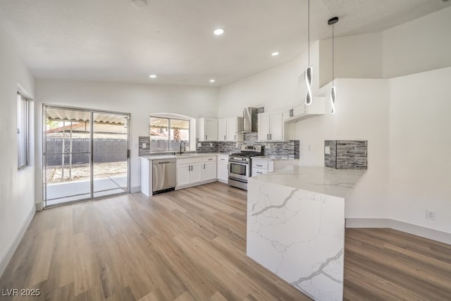 kitchen featuring white cabinetry, sink, hanging light fixtures, light stone counters, and stainless steel appliances