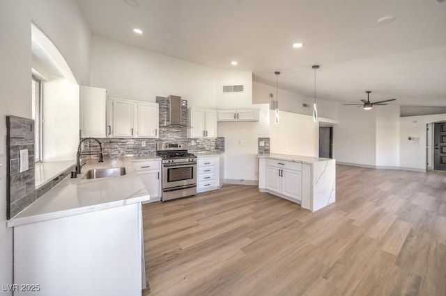 kitchen with white cabinetry, sink, wall chimney range hood, and stainless steel range with gas stovetop