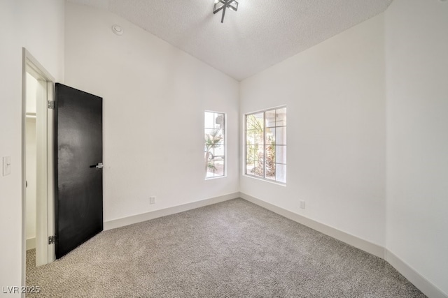 carpeted spare room featuring vaulted ceiling and a textured ceiling