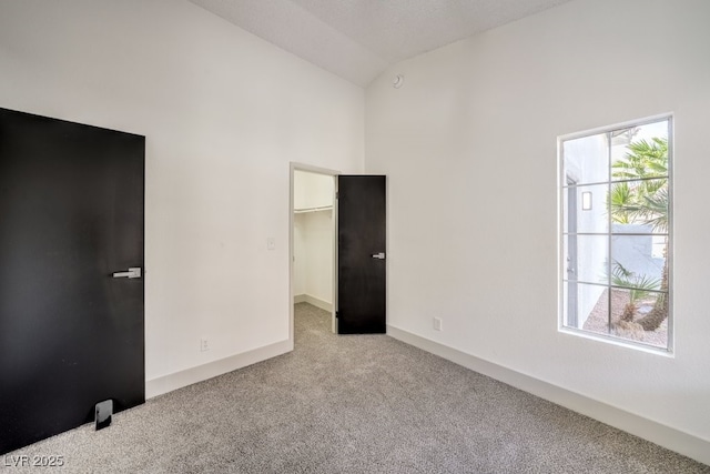 unfurnished bedroom featuring a walk in closet, lofted ceiling, light colored carpet, and a closet