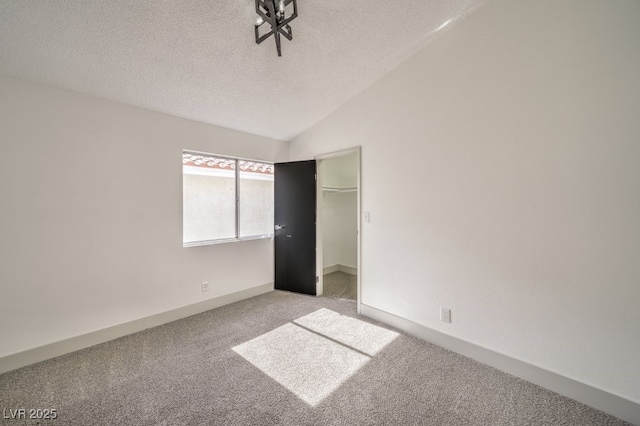 unfurnished bedroom with lofted ceiling, a spacious closet, light colored carpet, and a closet