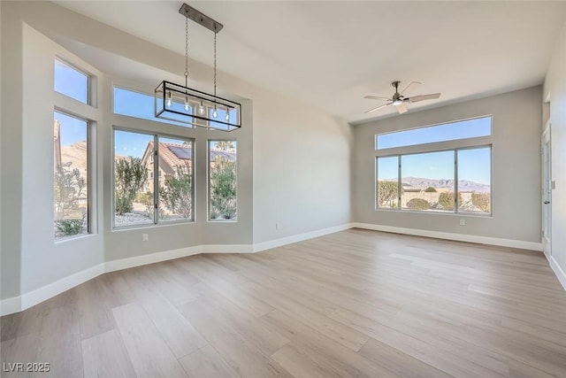 unfurnished living room with a mountain view, ceiling fan with notable chandelier, and light wood-type flooring