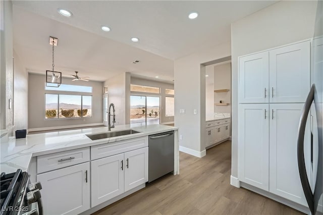 kitchen with sink, appliances with stainless steel finishes, pendant lighting, light stone countertops, and white cabinets