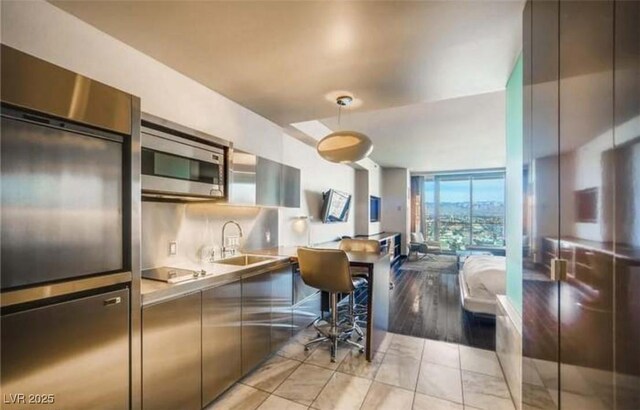 kitchen featuring light tile patterned flooring, floor to ceiling windows, sink, appliances with stainless steel finishes, and backsplash