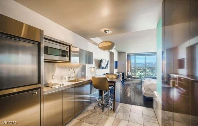 kitchen featuring sink, light tile patterned floors, floor to ceiling windows, tasteful backsplash, and black electric cooktop