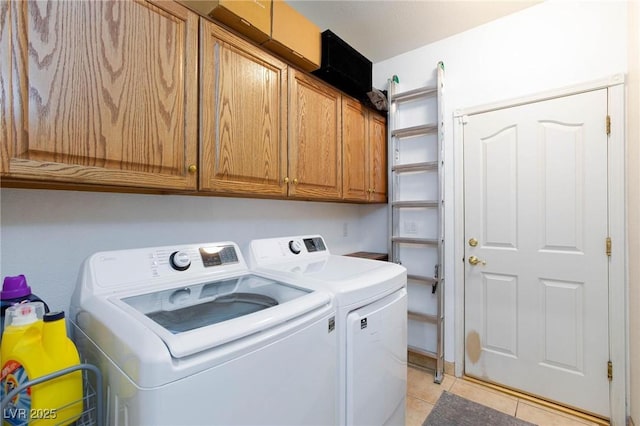 clothes washing area with cabinets, light tile patterned floors, and independent washer and dryer