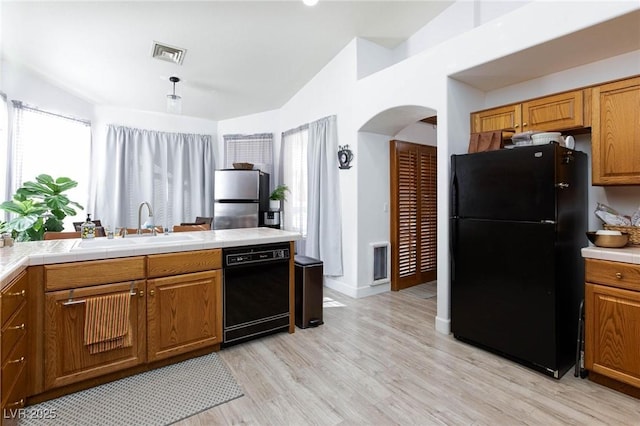 kitchen with lofted ceiling, sink, black appliances, and light wood-type flooring