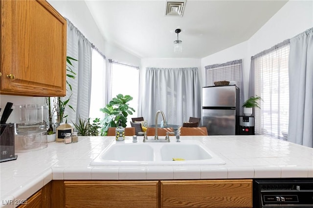 kitchen with sink, tile countertops, and stainless steel fridge