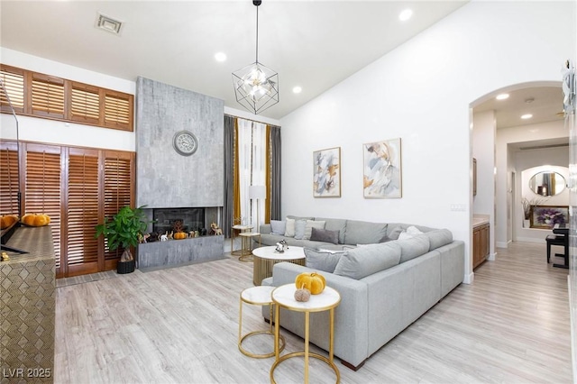 living room with a fireplace, vaulted ceiling, and light wood-type flooring