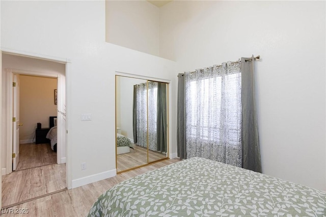 bedroom with wood-type flooring, a closet, and a high ceiling