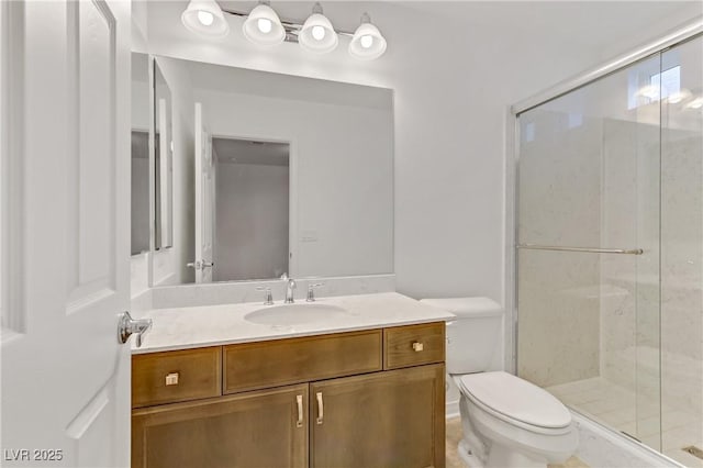 bathroom featuring vanity, a shower with shower door, and toilet