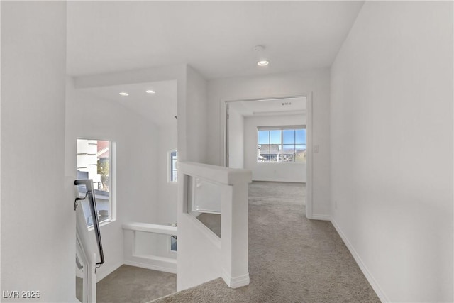 hall featuring lofted ceiling and light colored carpet