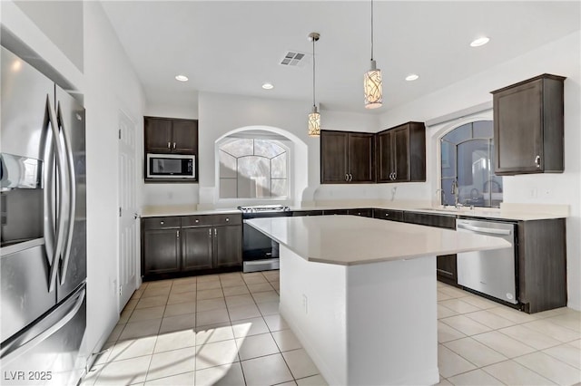 kitchen featuring sink, a center island, light tile patterned floors, dark brown cabinetry, and stainless steel appliances